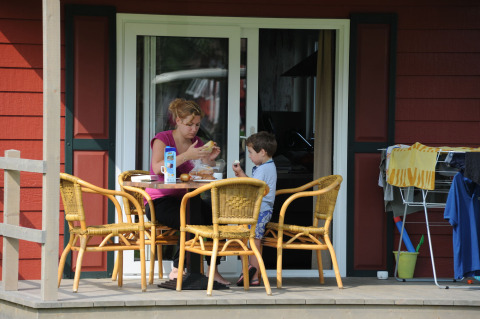 Eine Mutter und ihr Sohn frühstücken gemeinsam auf der Veranda im Veluwecamping De Pampel in Gelderland.