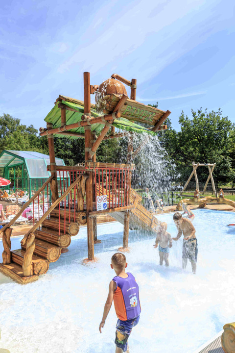 Kinderen spelen onder een grote wateremmer in het speelwaterpark van Veluwecamping De Pampel, Gelderland.
