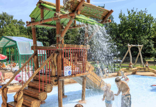 Des enfants jouent sous un grand seau d'eau à l’aire de jeux aquatiques de Veluwecamping De Pampel, Gelderland.