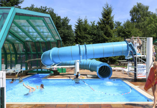Piscina all'aperto con scivolo blu al Veluwecamping De Pampel, parco vacanze in Gheldria, Paesi Bassi.