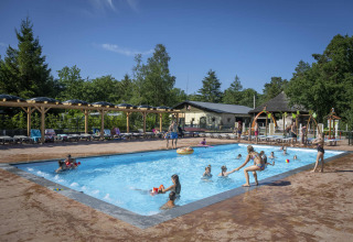 Familien und Kinder entspannen sich an einem sonnigen Pool bei Veluwecamping De Pampel in Gelderland, Niederlande.