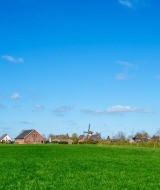Campos verdes y casas bajo un cielo azul en un parque vacacional que ofrece alojamientos glamping.