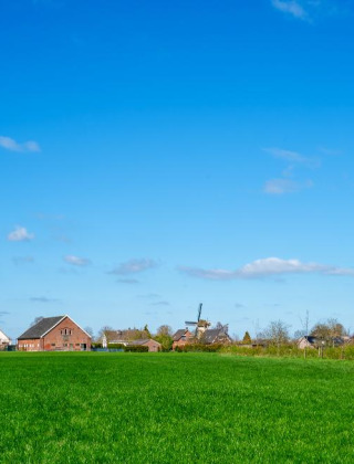 Campos verdes y casas bajo un cielo azul en un parque vacacional que ofrece alojamientos glamping.