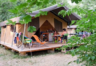 Gezin zit voor een lodgetent bij Huttopia Millau, een vakantiepark in Occitanië, Frankrijk.