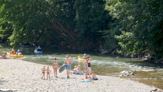 Familias disfrutan del río y actividades acuáticas en Huttopia Millau, parque de vacaciones en Occitania, Francia.