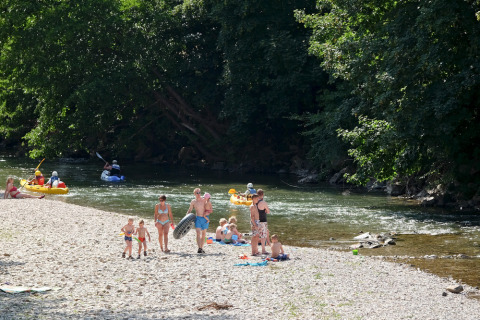 Famiglie si godono il fiume e il kayak al villaggio vacanze Huttopia Millau in Occitania, Francia.