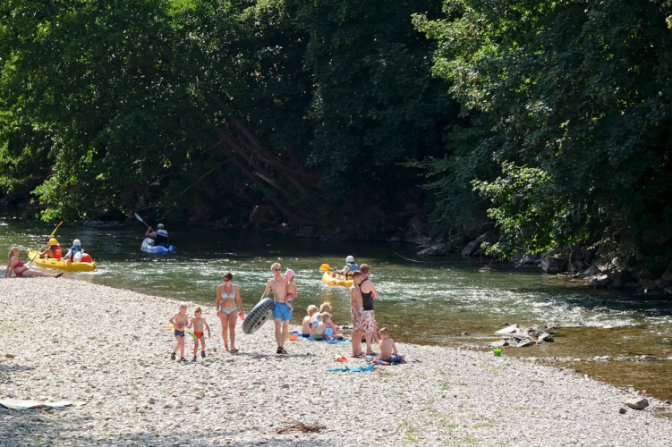 Des familles profitent de la rivière et du canoë au parc de vacances Huttopia Millau en Occitanie, France.