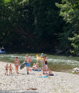 Familias disfrutan del río y actividades acuáticas en Huttopia Millau, parque de vacaciones en Occitania, Francia.