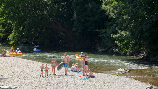 Familias disfrutan del río y actividades acuáticas en Huttopia Millau, parque de vacaciones en Occitania, Francia.