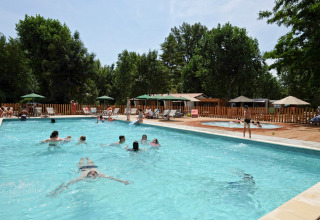 Gasten zwemmen en relaxen aan het zwembad van Huttopia Millau vakantiepark in Occitanië, Frankrijk.