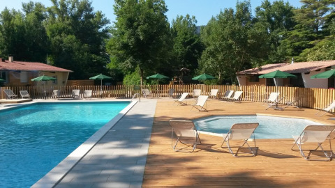Piscina exterior y zona de spa con tumbonas y sombrillas en Huttopia Millau, Occitanie, Francia.