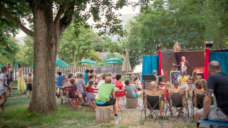 Niños y adultos disfrutan de un espectáculo al aire libre en Huttopia Millau, parque vacacional en Occitania, Francia.