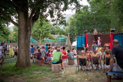 Kinderen en volwassenen genieten van een openluchttheater in Huttopia Millau vakantiepark in Occitanië, Frankrijk.