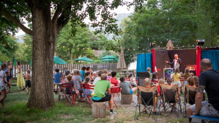 Niños y adultos disfrutan de un espectáculo al aire libre en Huttopia Millau, parque vacacional en Occitania, Francia.