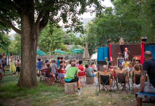 Kinderen en volwassenen genieten van een openluchttheater in Huttopia Millau vakantiepark in Occitanië, Frankrijk.