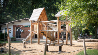 Parque infantil con estructura de madera en el parque vacacional Huttopia Millau en Occitania, Francia.