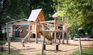 Aire de jeux avec structure en bois au parc de vacances Huttopia Millau en Occitanie, France.