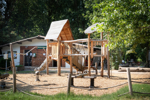 Parque infantil con estructura de madera en el parque vacacional Huttopia Millau en Occitania, Francia.