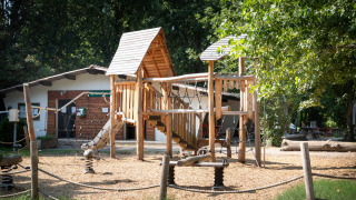 Parque infantil con estructura de madera en el parque vacacional Huttopia Millau en Occitania, Francia.