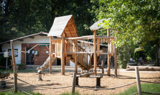 Parque infantil con estructura de madera en el parque vacacional Huttopia Millau en Occitania, Francia.