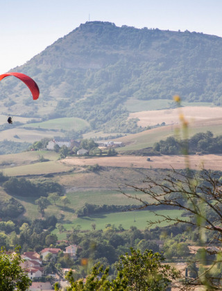 Dos parapentes vuelan sobre las colinas que rodean Millau, en Occitania, Francia, en un día despejado.