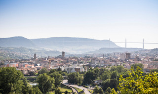 Vista de Millau en Occitania, Francia, con los tejados del pueblo y el icónico viaducto de Millau al fondo.