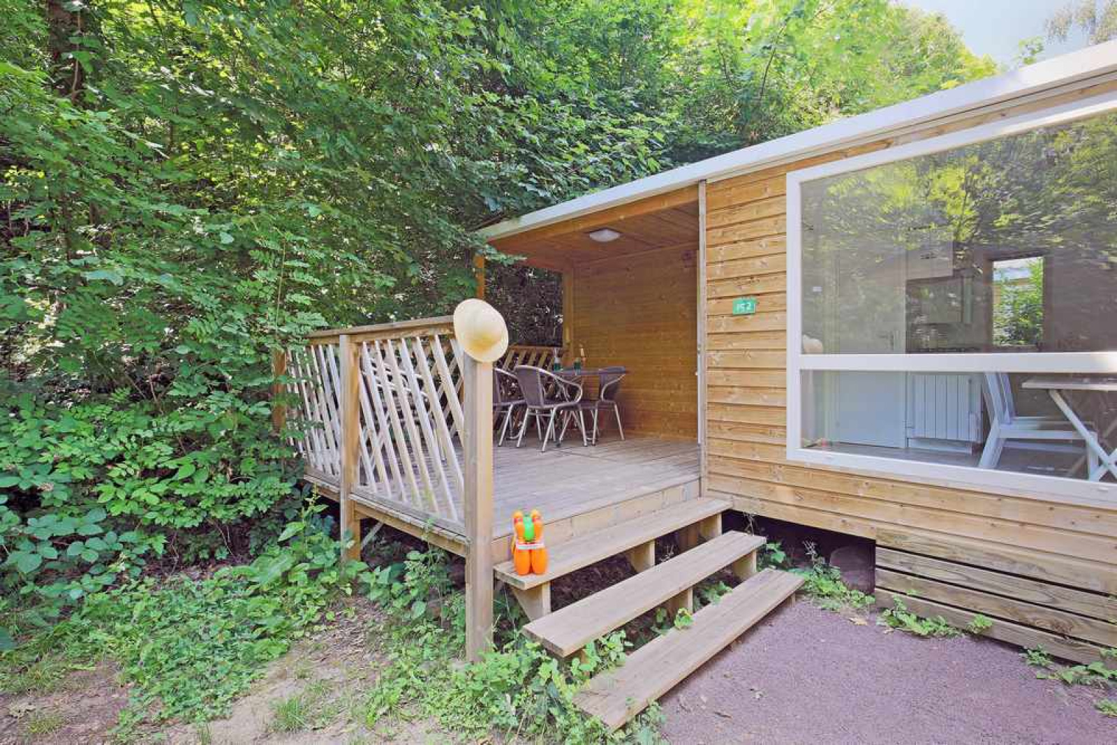 Mobile home Cottage bij Huttopia Millau in Frankrijk, houten huisje omgeven door groene natuur.
