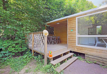 Træhytte Mobile home Cottage ved Huttopia Millau i Frankrig, omgivet af frodig skov og natur.