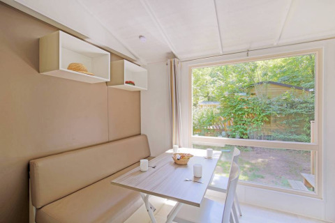 Lyst spiseområde i Mobile home Cottage på Huttopia Millau, Frankrig, med udsigt til grøn have.