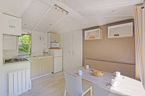 Lys og moderne hytte med køkken og spisebord på Mobile home Cottage, Huttopia Millau, Frankrig.