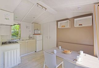 Lys og moderne hytte med køkken og spisebord på Mobile home Cottage, Huttopia Millau, Frankrig.