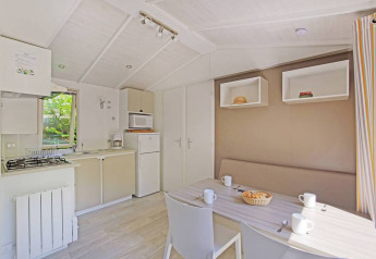 Lys og moderne hytte med køkken og spisebord på Mobile home Cottage, Huttopia Millau, Frankrig.