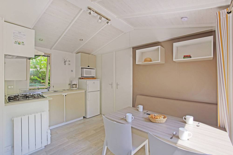 Cabaña luminosa y moderna con cocina y mesa de comedor en Mobile home Cottage, Huttopia Millau, Francia.