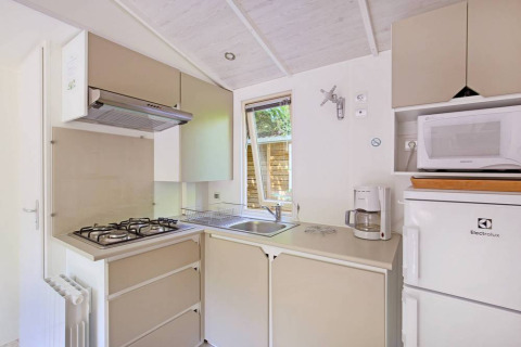 Moderne, kompakt køkken i en Mobile home Cottage på Huttopia Millau, med gasblus, vask og apparater.
