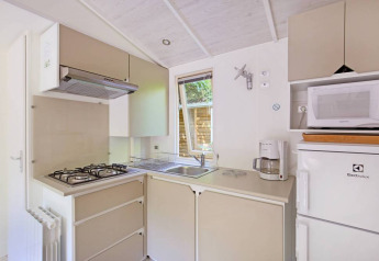 Modern ausgestattete Küche in einem Mobile Home Cottage bei Huttopia Millau mit Herd und Geräten.