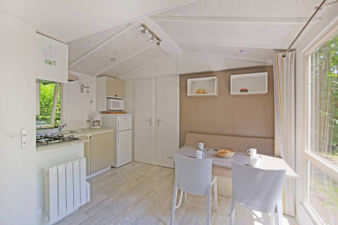 Lyst og moderne køkken og spisestue i en Mobile home Cottage på Huttopia Millau, Frankrig, med udsigt til skov.