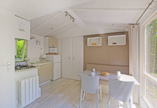 Cocina y comedor modernos y luminosos en una Mobile home Cottage en Huttopia Millau, Francia, con vistas al bosque.