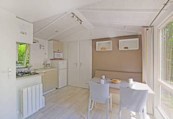 Lyst og moderne køkken og spisestue i en Mobile home Cottage på Huttopia Millau, Frankrig, med udsigt til skov.