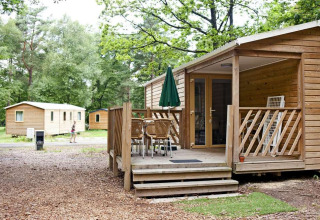 Træhytte med terrasse og havemøbler i skovmiljø ved Mobile Home Cottage på Huttopia Millau, Frankrig.