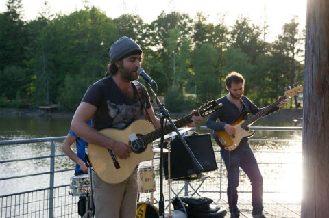 Músicos tocan en un concierto al aire libre junto al lago en Village Huttopia Senonches, Centre-Val de Loire, Francia.