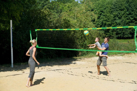 Familia jugando voleibol en una cancha de arena en el parque Village Huttopia Senonches en Centre-Val de Loire, Francia.