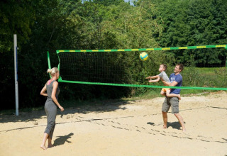Gezin speelt volleybal op een zandterrein aan Village Huttopia Senonches vakantiepark in Centre-Val de Loire, Frankrijk.
