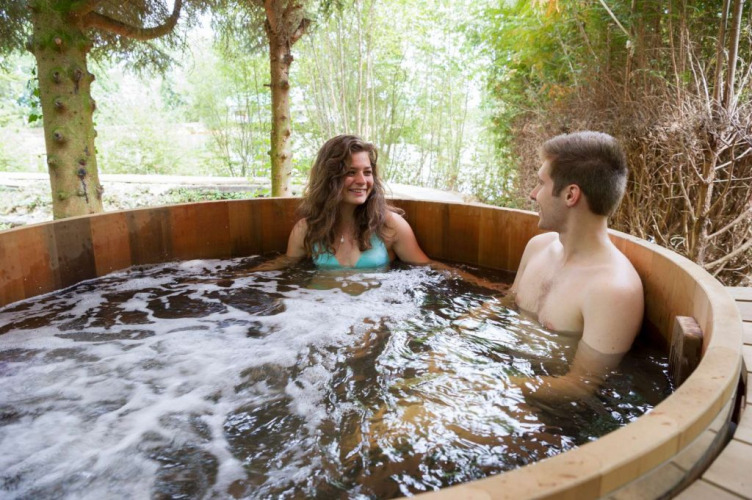 Twee mensen ontspannen zich in een buitenspa bij Village Huttopia Senonches, Centre-Val de Loire, Frankrijk.