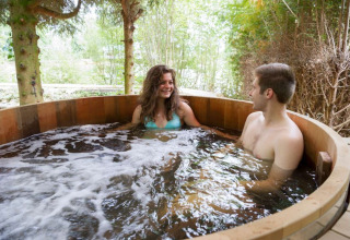 Two people relaxing in an outdoor hot tub at Village Huttopia Senonches, Centre-Val de Loire, France.