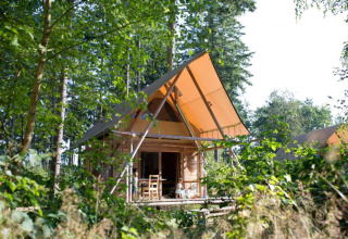 Gezellige houten hut met tentdak tussen bomen in Village Huttopia Senonches, Centre-Val de Loire, Frankrijk.