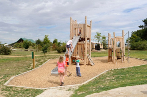 Niños juegan en un parque infantil con tobogán y juegos de trepar en Village Huttopia Senonches, Francia.