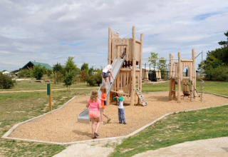 Niños juegan en un parque infantil con tobogán y juegos de trepar en Village Huttopia Senonches, Francia.