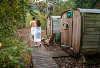 Koppel wandelt naar de sauna’s bij Village Huttopia Senonches, een vakantiepark in Centre-Val de Loire, Frankrijk.