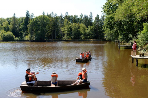 Kinderen met zwemvesten varen met bootjes op een meer bij Village Huttopia Senonches, Centre-Val de Loire, Frankrijk.