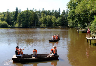Kinderen met zwemvesten varen met bootjes op een meer bij Village Huttopia Senonches, Centre-Val de Loire, Frankrijk.